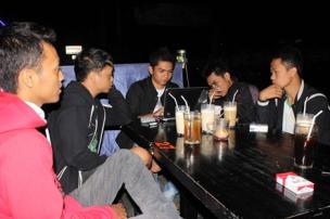 Sekelompok mahasiswa sedang berkumpul di cafe dekat kampus dengan suasana ramai.