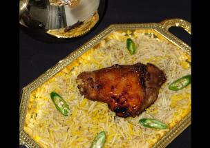 Sepiring nasi mandhi dengan potongan ayam bakar dan taburan rempah.