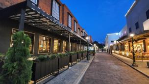 Gambar jalanan ramai di Tebet dengan kafe dan ruko, dan deretan townhouse modern.