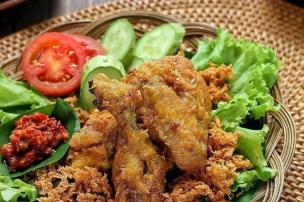Sepiring ayam goreng dengan kremesan, sambal, dan lalapan.