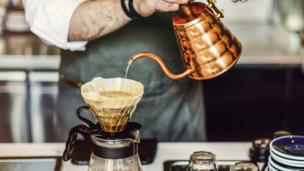 Barista sedang membuat kopi dengan metode manual brew di coffee shop yang estetik.
