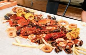 Meja penuh dengan aneka hidangan seafood segar yang disajikan di restoran.