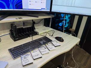 Teknisi sedang menganalisis hard drive di meja laboratorium.