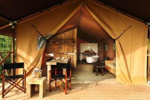 Interior tenda glamping mewah dengan tempat tidur nyaman, dekorasi estetik, dan pemandangan alam.