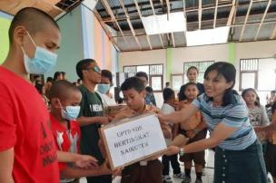Gambar siswa-siswi sedang membagikan bantuan atau mengajar di panti asuhan sebagai bagian dari kegiatan sosial sekolah.