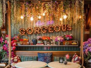 Interior cafe dengan dekorasi unik bertema taman fantasi, penuh bunga dan lampu.