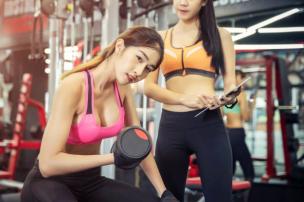Wanita sedang berolahraga di gym khusus wanita, suasana ceria dan suportif.