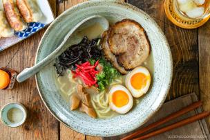 Semangkuk ramen dengan kuah kental, telur, dan chashu yang tersaji di meja.