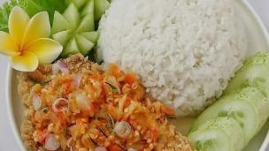 Sepiring ayam geprek sambal matah dengan nasi hangat dan lalapan di meja.