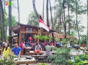 Beberapa orang sedang menikmati kopi di area outdoor Armor Kopi Garden dengan latar belakang hutan pinus.