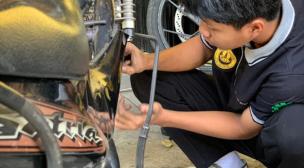 Mekanik sedang memperbaiki mesin motor di sebuah bengkel sederhana.