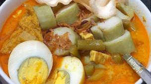 Semangkuk lontong sayur dengan kuah santan dan telur rebus.