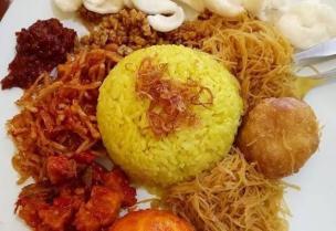 Seporsi nasi kuning komplit dengan telur, bihun, tempe orek, dan lauk lainnya.