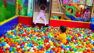 Anak-anak sedang bermain ceria di playground indoor dengan kolam bola dan perosotan.
