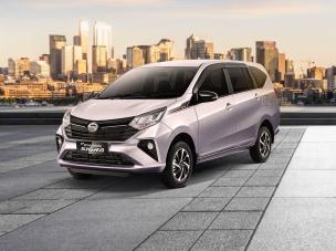 Gambar Daihatsu Sigra perak melaju di jalan kota yang sibuk di siang hari, menonjolkan ukuran kompak dan penggunaan praktisnya, dengan latar belakang samar Bekasi.