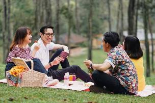 Keluarga sedang piknik di Taman Lansia Bandung dengan anak-anak bermain di rumput.