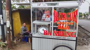 Gerobak penjual batagor di pinggir jalan dengan pembeli yang mengantre.