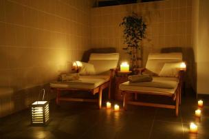 Interior ruangan spa yang tenang dengan aroma terapi, bunga, dan handuk yang tertata rapi.