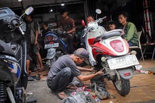  Montir sedang memeriksa bagian mesin skuter matic