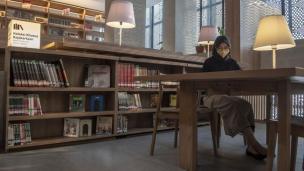 Gambar interior perpustakaan umum modern dengan orang-orang yang membaca.