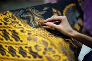 Tangan sedang mencanting batik di sebuah workshop batik tradisional.