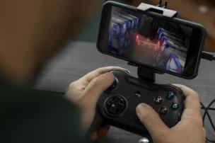 Ponsel terpasang pada kontroler gaming ergonomis, siap untuk bermain game.