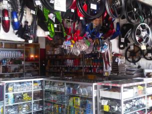 Gambar toko suku cadang dan aksesoris motor yang lengkap, dengan rak-rak penuh barang, dan beberapa motor pilihan yang dipajang untuk dijual.