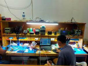Teknisi sedang memperbaiki tablet di meja servis dengan alat-alat khusus.