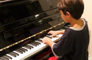 Seseorang sedang belajar bermain piano di sebuah studio musik.