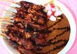 Piring sate ayam dengan bumbu kacang dan irisan bawang merah.