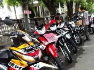 Gambar pasar motor bekas (bursa motor) outdoor yang ramai dengan banyak motor dipajang dan pembeli berjalan-jalan.