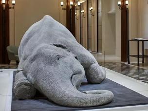 Gambar lobi hotel yang dihiasi dengan karya seni kontemporer dan patung.