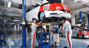 Montir sedang memeriksa mesin mobil di bengkel umum