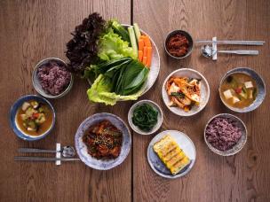 Meja makan berisi berbagai hidangan Korean BBQ dengan kimchi dan banchan.