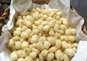 Gambar semangkuk pilus yang renyah dengan taburan bumbu, diletakkan di samping piring bakso atau mi ayam.