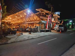 Suasana warmindo yang ramai di malam hari dengan mahasiswa yang begadang.