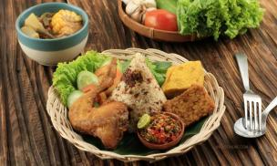 Semangkuk Nasi Tutug Oncom dengan lauk sederhana seperti tahu tempe goreng di piring tradisional.