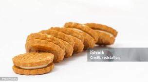 Gambar beberapa keping biskuit dengan isian krim susu dan segelas susu di sampingnya.