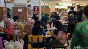 Suasana food court yang ramai dengan berbagai stall makanan dan pengunjung yang sedang makan.