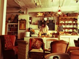 Interior kafe dengan tema klasik vintage, perabot antik, dan pencahayaan hangat.