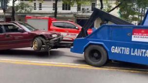 Mobil derek sedang membantu mobil mogok di pinggir jalan pada siang hari.