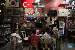 Anak muda berfoto di kafe bertema 80-an dengan dekorasi vintage dan warna cerah.