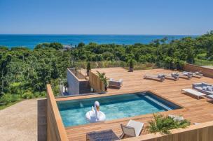 Gambar rumah mewah modern dengan kolam renang infinity dan pemandangan kota.